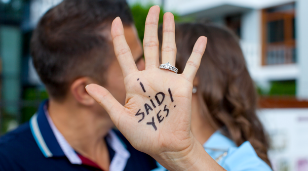 Newly engaged couple kissing and announcing their engagement through photos.